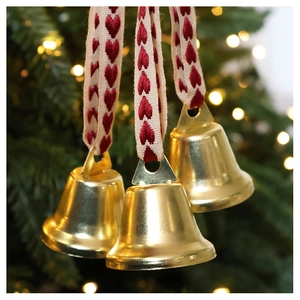 Close-up of golden Christmas bells with red and white heart-patterned ribbons on a tree