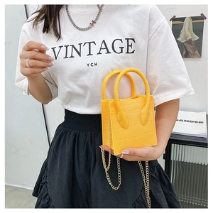Detail view of a yellow crocodile-patterned mini bag with a luxury gold chain strap