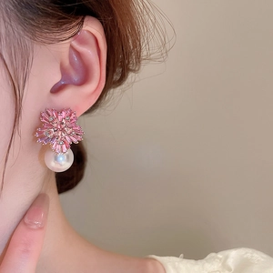 Detail of pink crystal flower earrings with white pearl drop on model ear