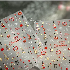 Détail de stickers pour ongles de Noël avec pomme rouge, arbres dorés et nœuds