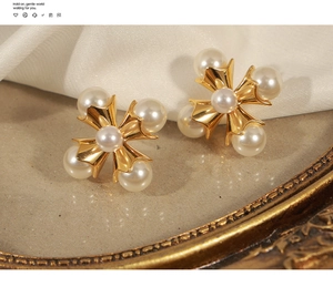 Macro detail of vintage gold cross earrings with pearls on a decorative mirror