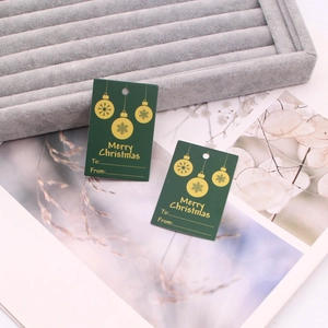 Detailed view of forest green Merry Christmas gift tags on a gray velvet tray
