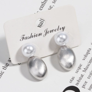Elegant brushed silver metal oval earrings with white pearls on a display card