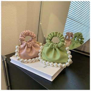 Detail of pink and green girls' faux leather pearl handle bags with gold chain straps