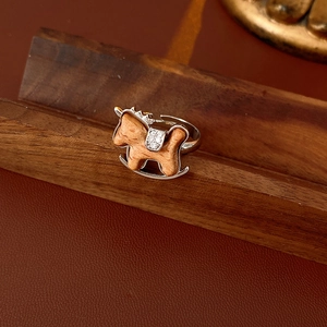 Detail of a silver rocking horse ring with zircon saddle on a dark wood background