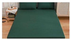 Detail view of dark green fitted sheet set and matching pillowcases on a wooden bed