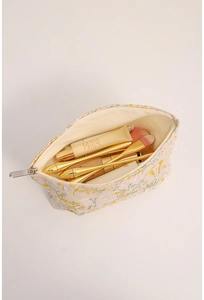 Vue de dessus d'une trousse en lin brodé fleurs ouverte avec des produits cosmétiques