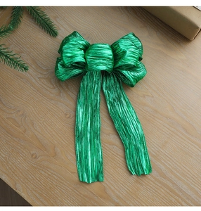Close-up of green glitter fabric Christmas bow on rustic wooden background
