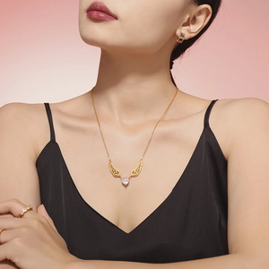 Golden angel wing heart zircon necklace with matching earrings on a model in studio