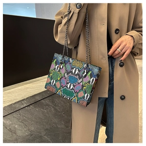 Close-up of stylish python print patchwork handbag with dark metal chain straps
