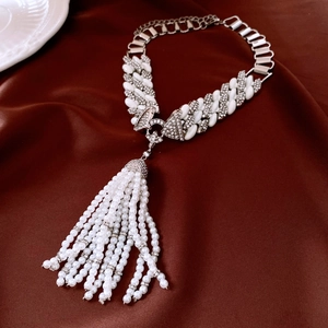 Detailed view of layered pearl tassel pendant with silver metal fringe on satin