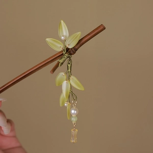 Detail of wooden hair pin with pale green leaves, white pearls and gold bead tassels