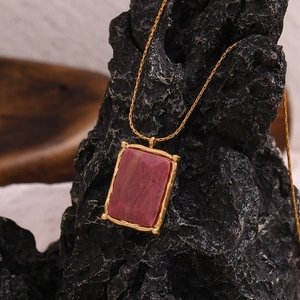 Macro shot of gold plated necklace featuring a rectangular pink natural stone pendant
