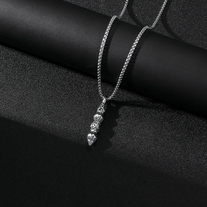 Gros plan du pendentif vajra en acier argenté sur chaîne box avec fond noir texturé