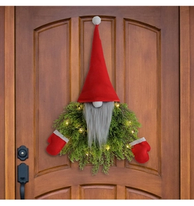 Close-up of lighted Christmas gnome wreath with warm white LED on a dark wooden door