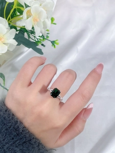 Detail of emerald cut green gemstone ring with pavé diamonds on a hand