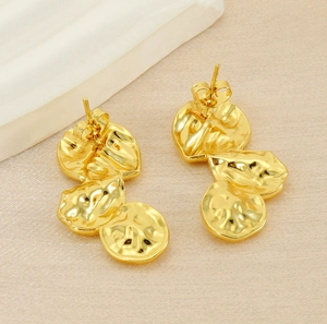 Detailed view of French vintage irregular gold pleated petal drop earrings on beige fabric