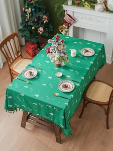 Detail of green Christmas tablecloth featuring reindeer embroidery and white fringe edges