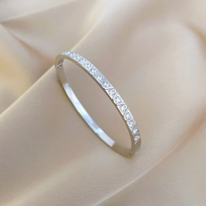 Elegant silver stainless steel bangle with circular zirconia inlay on champagne velvet