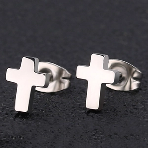 Macro detail of silver stainless steel cross stud earrings on a textured gray background