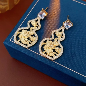 Macro shot of gold-plated hollow gourd earrings with cubic zirconia on a jewelry box