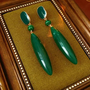 Detail view of vintage gold drop earrings with malachite beads on green velvet