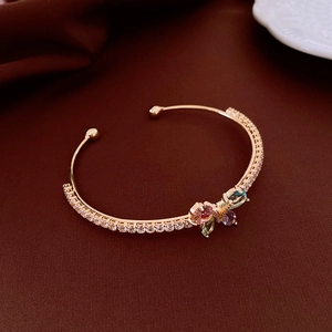 Détail macro du bracelet jonc doré orné d'un papillon en pierres colorées et zircons