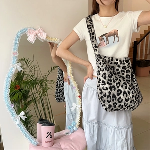Lifestyle view of a large leopard print canvas crossbody bag worn by a model in a cafe