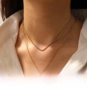 Detail of double-layer gold necklace set with heart pendant and tennis chain on model
