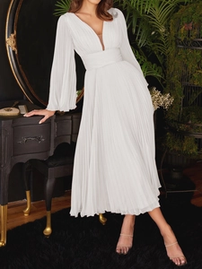Elegant white pleated midi dress with deep V-neck and long lantern sleeves in vintage room