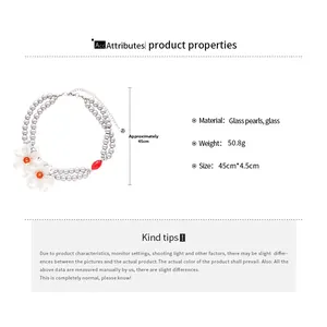Close-up of double-layer glass pearl necklace with white flower and red bead detail
