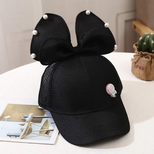 Detail of kids baseball cap with pearl bow and pink lollipop badge on black mesh fabric