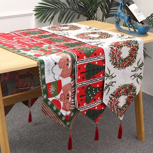 Knitted Christmas table runner with Santa Claus pattern and red tassels on wooden table