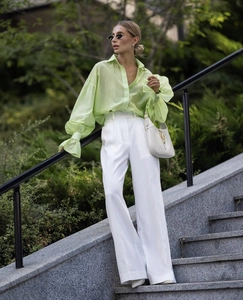 Detail of light green puff sleeve shirt paired with high-waisted white wide-leg trousers