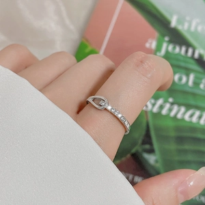 Minimalist silver knotted ring with cubic zirconia accents worn on a hand model