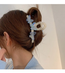Detail of a white hair claw with iridescent blue butterflies on a model's hair