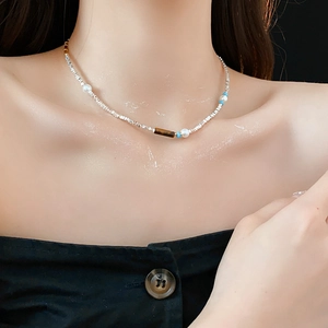 Detail of necklace with silver beads, brown tiger eye, pearls and blue turquoise on a model