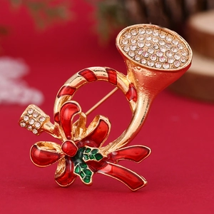 Detail of Christmas trumpet brooch with gold metal, green enamel and red bow rhinestones