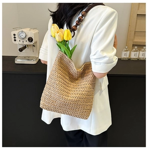 Detail of hand-woven straw shoulder bag with wooden bead strap and tulip decoration