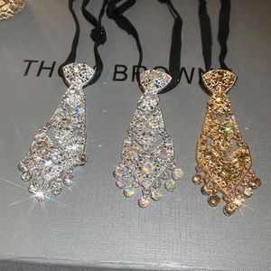 Detailed view of three rhinestone tie-shaped necklaces in silver and gold with elastic bands