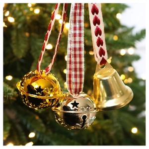 Detail of metal star-cutout bells with red checkered ribbons on green Christmas tree branches
