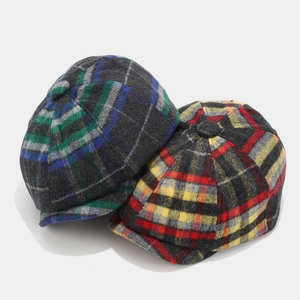 Detail of wool blend newsboy caps showing blue and red plaid patterns and warm texture