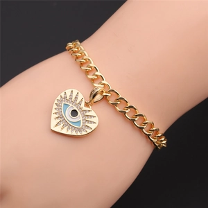 Detailed view of a gold-plated Cuban chain bracelet with a heart-shaped Evil Eye charm
