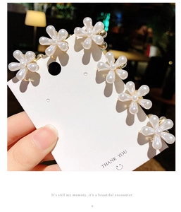 Détail de six pinces à cheveux en forme de fleur de perle sur une carte de présentation