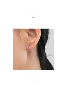 Detail showing elegant silver hoop earrings with pink zircons on female model's ear