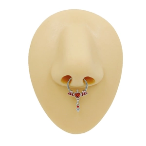 Anneau de septum argenté avec pendentif cœur ailé rouge sur un modèle de nez