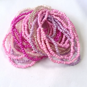 Macro detail of multi-layered colorful glass seed bead bracelets in pink and purple tones