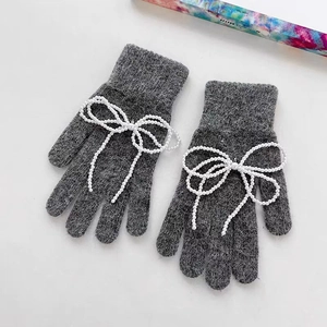 Close-up of grey knitted gloves featuring elegant white pearl bow decorations