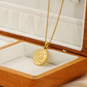Detailed close-up of golden stainless steel Libra zodiac pendant in a wooden box