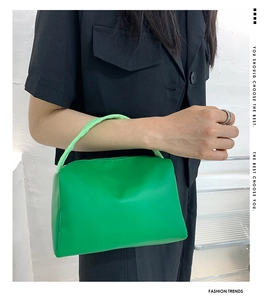 Lifestyle view of a green trapezoid handbag with a ruffled handle for fashionable women
